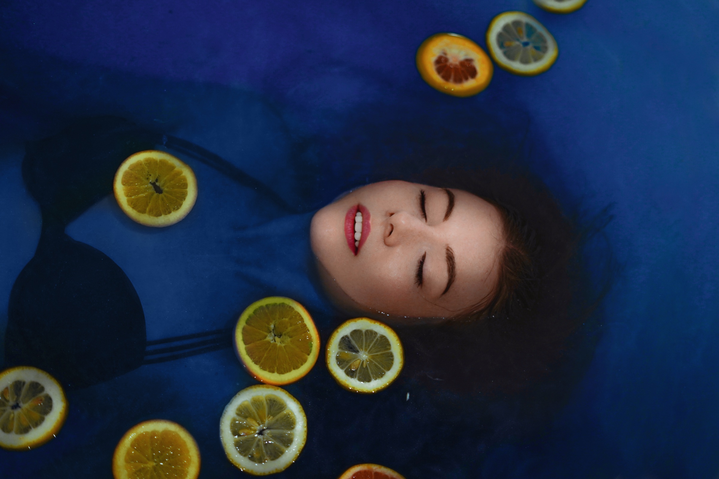 Conceptual portrait with citrus fruit on blue
